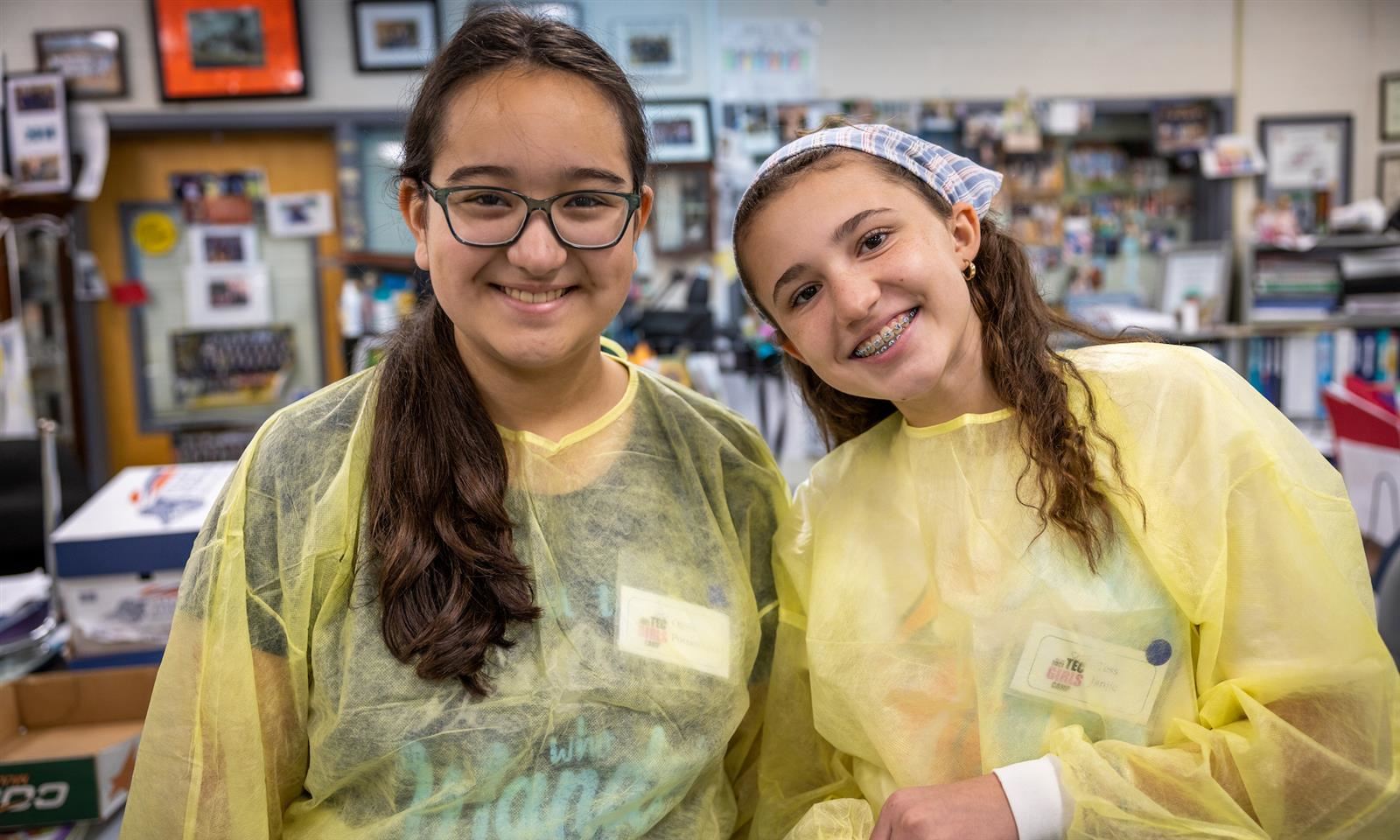 Two girls wearing protective gear smile